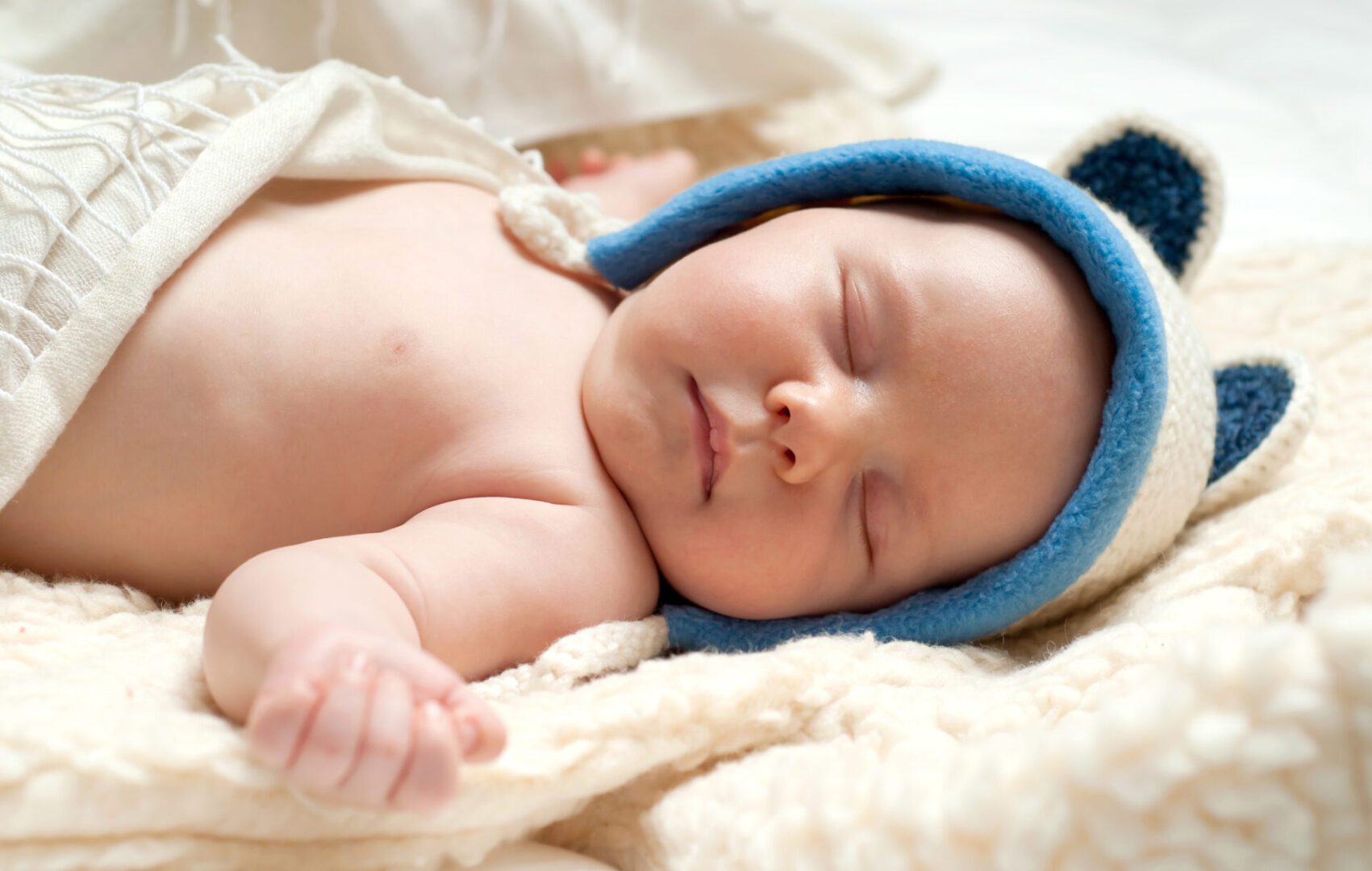 Sleeping baby wearing blue bear hat.
